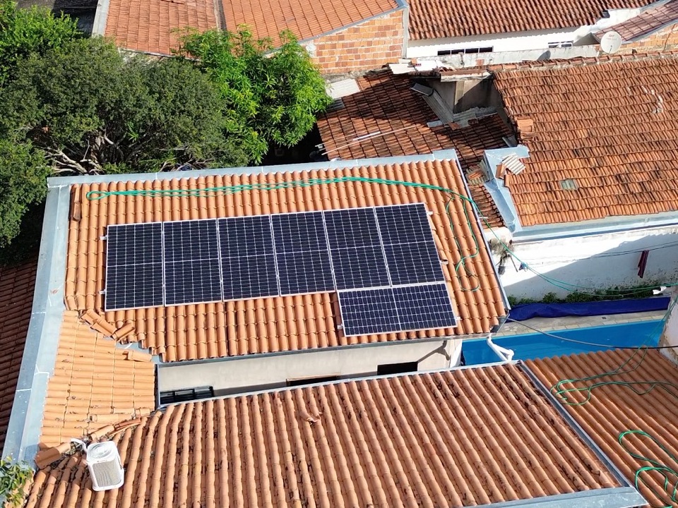 Sistema de energia solar no telhado de telha cerâmica de uma casa com piscina, visto de drone
